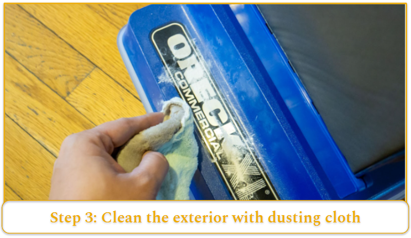 A dusting cloth wiping down the outside of a vacuum’s brush head