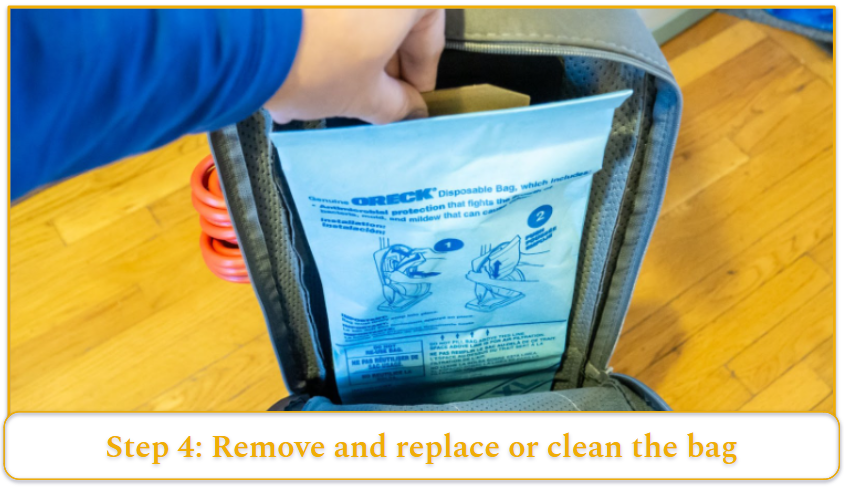 A dust bag being removed from an upright vacuum