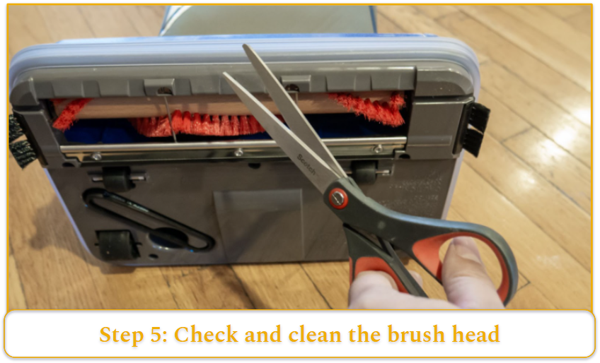 A pair of scissors in front of an upturned vacuum cleaner