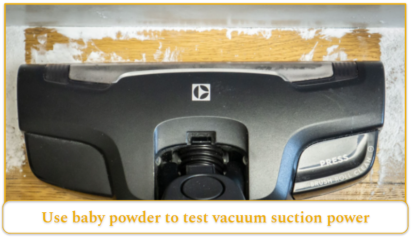 A vacuum brush head cleaning up baby powder on a hardwood floor