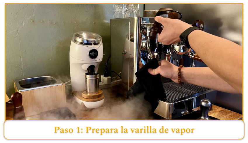 step 1 of using an espresso machine's steam wand; holding a towel to the tip of the steam wand and running it for 2-3 seconds