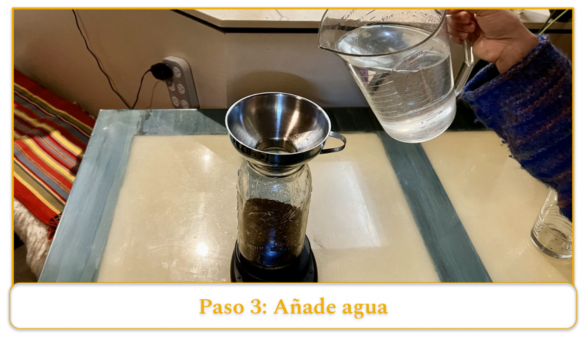 step 3 of making cold brew coffee; adding water to coffee grounds using a funnel